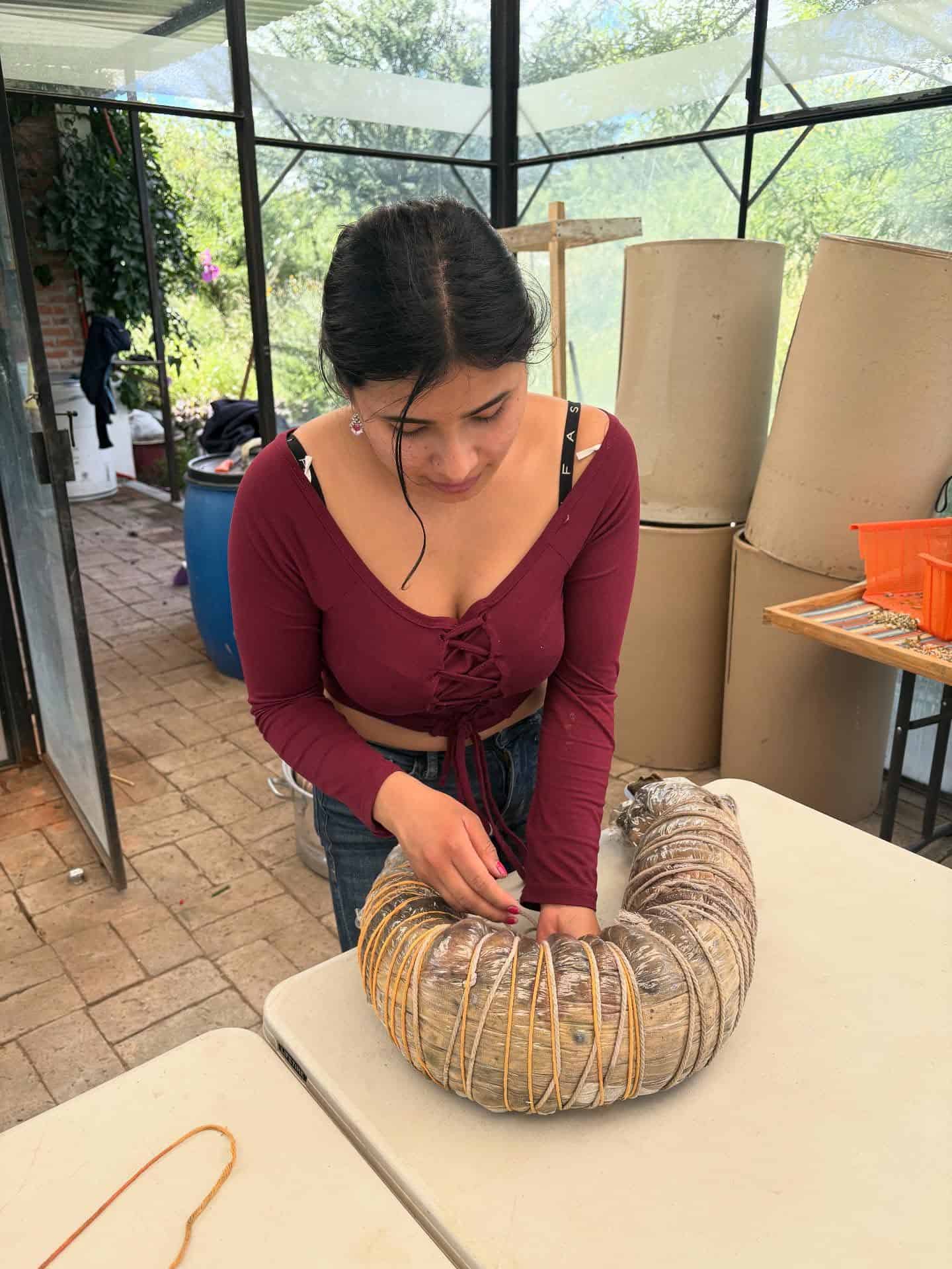 Woman creating a woven art piece with natural materials at a San Miguel Community Foundation event.